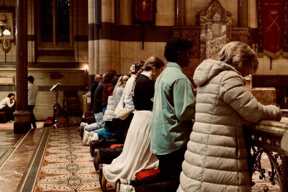 A congregation kneeling in prayer at a communion rail.
