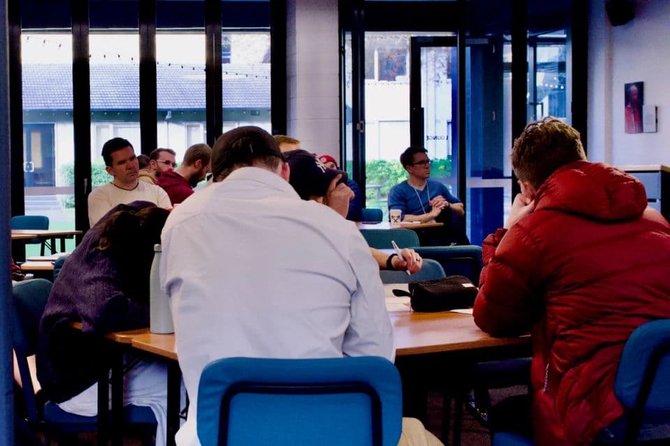 Leaders seated at long tables in a workshop session.
